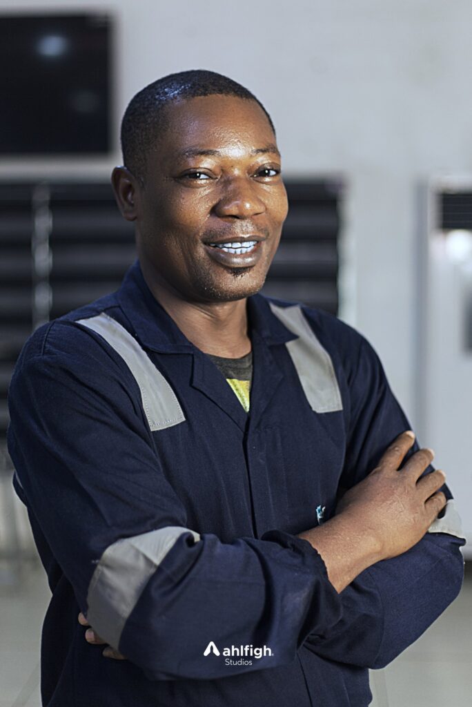 Carlos staff portrait: navy coveralls with reflective stripes, arms crossed