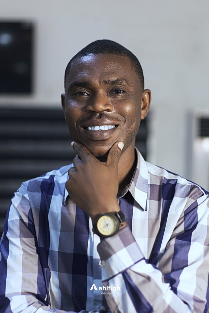 Carlos staff portrait: a checked shirt, hand at the chin