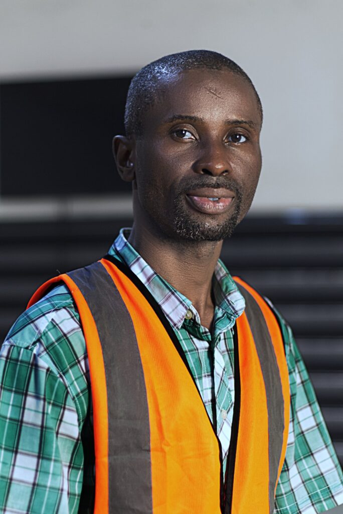 Carlos staff portrait: a checked shirt under an orange safety vest
