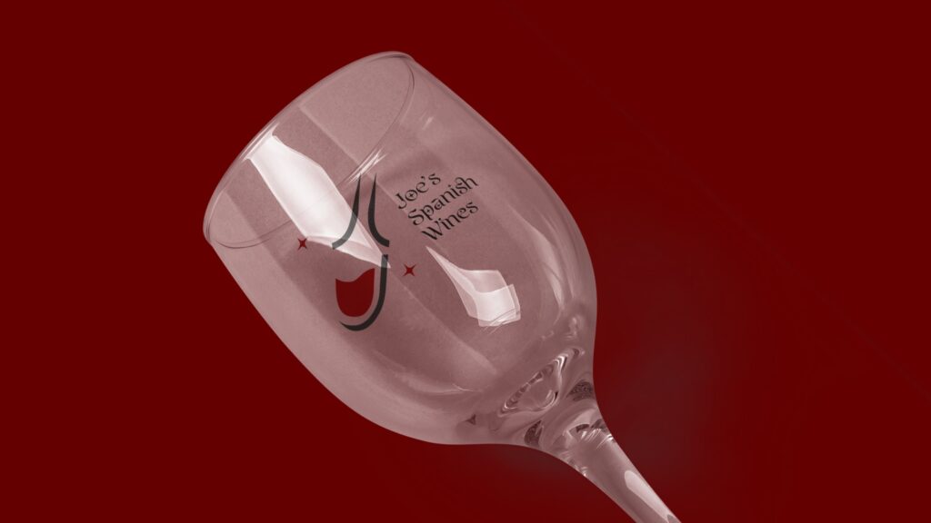 A wine glass etched with the logo, on red
